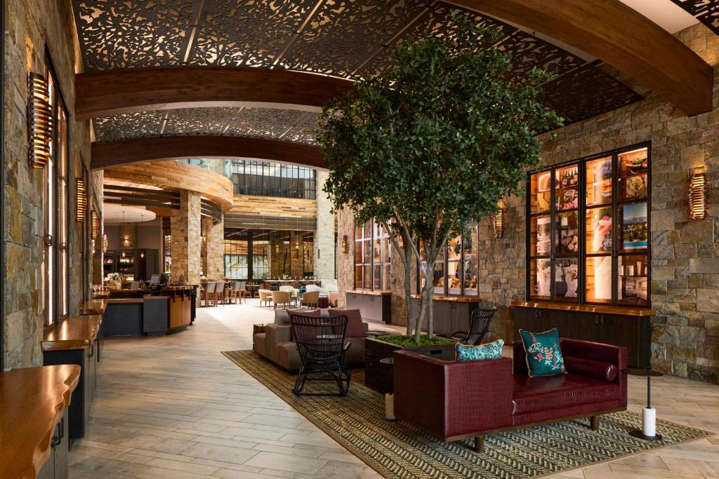 Luxurious hotel lobby with comfortable seating and a large tree, featuring a sophisticated design.