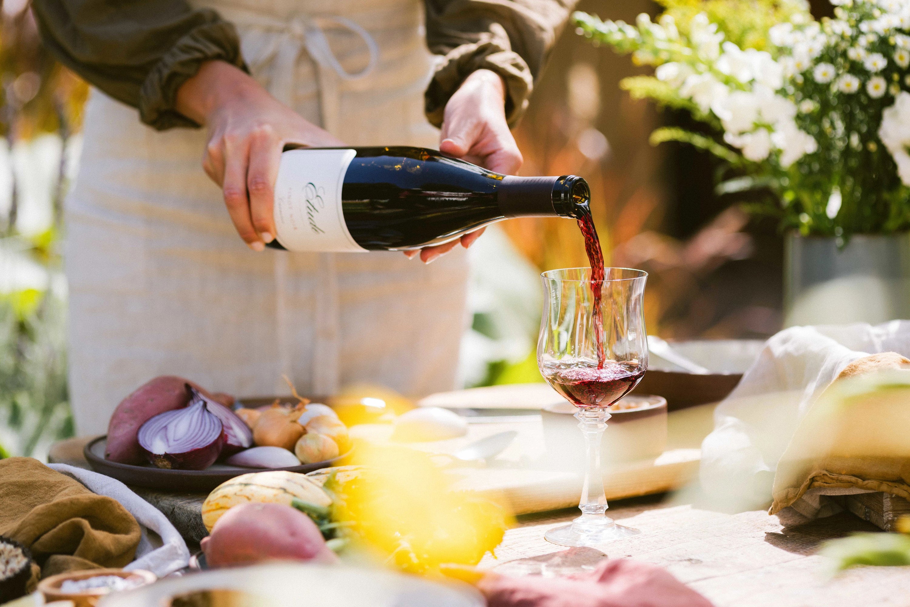 Person pouring red wine from Etude Wines bottle into glass.
