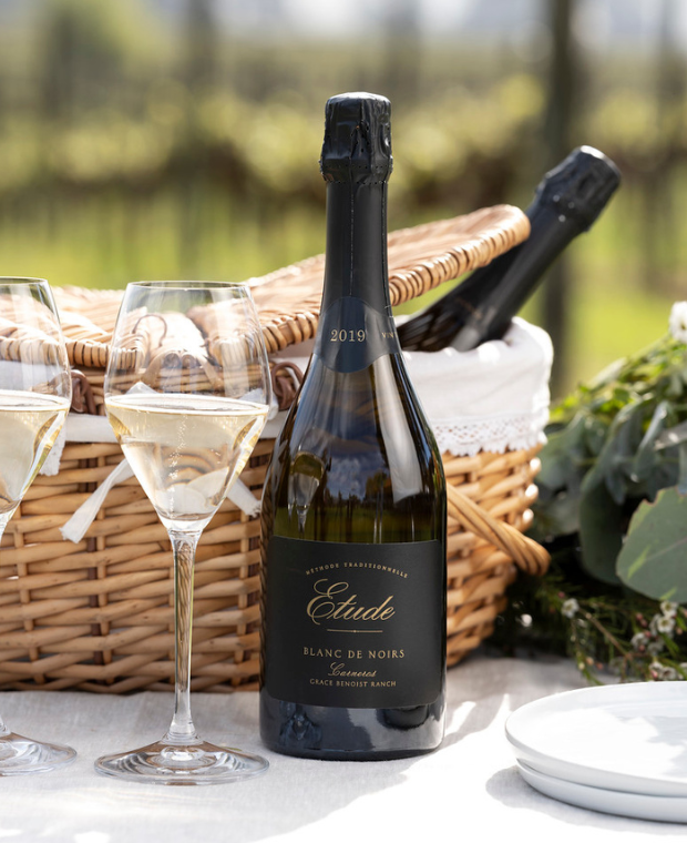 Bottle of Etude Blanc de Noirs sparkling wine in picnic basket with champagne flutes.