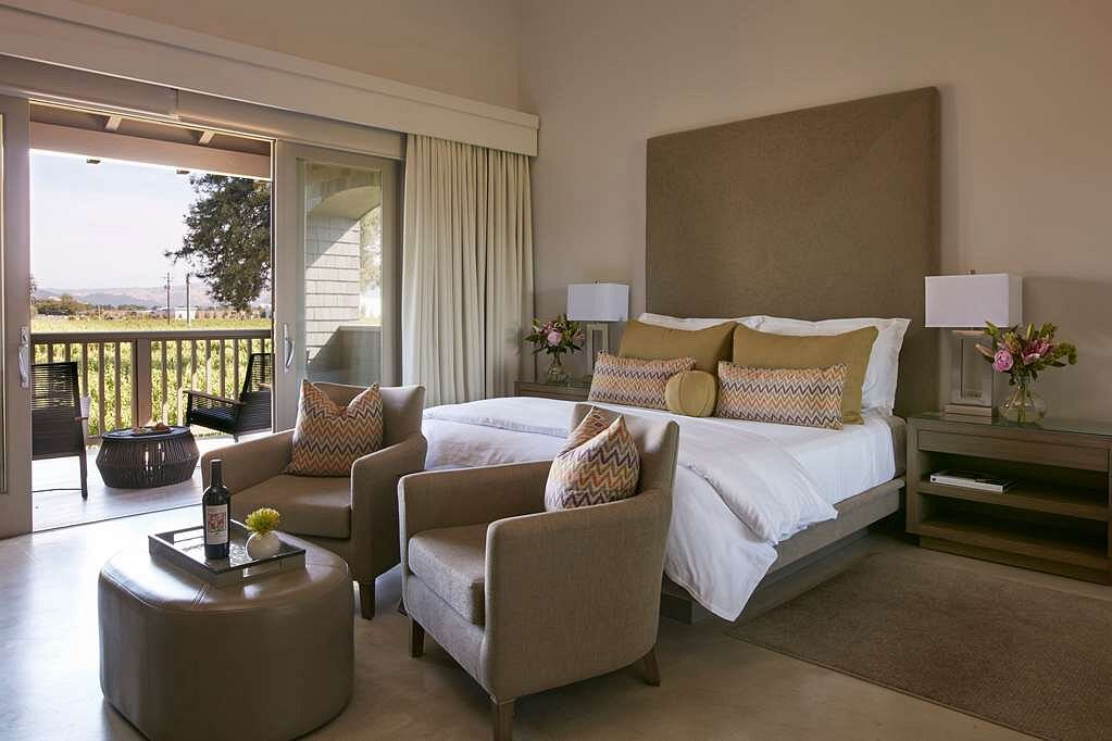 Luxurious hotel room with vineyard view, featuring comfortable seating and a king-size bed.