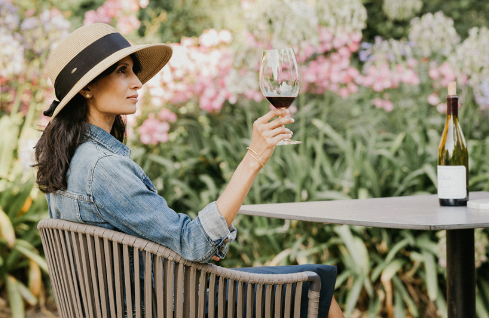 Woman in sun hat enjoys red wine outdoors