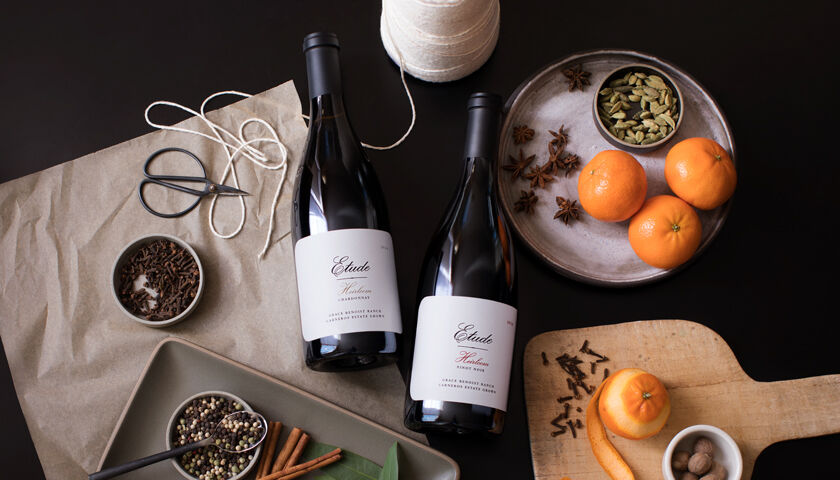 Two bottles of Etude wine on a table with spices and oranges.