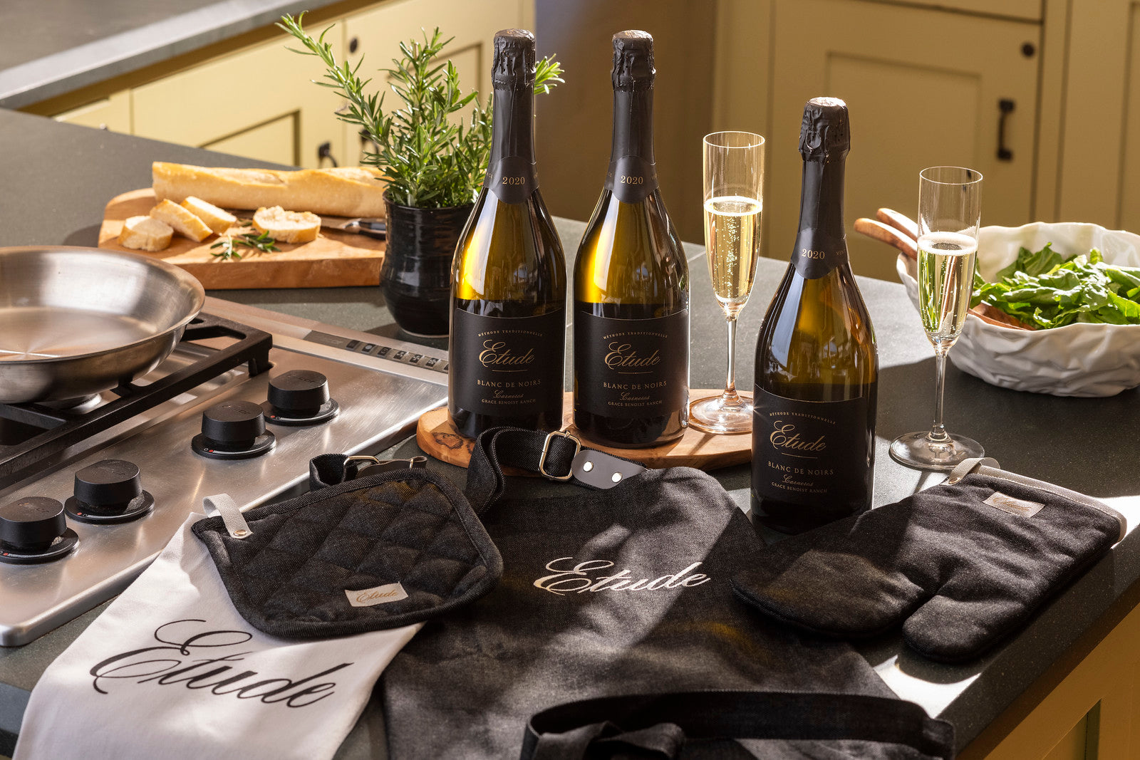 Three bottles of Etude Blanc de Noirs sparkling wine on a kitchen island with the Etude Chef Set
