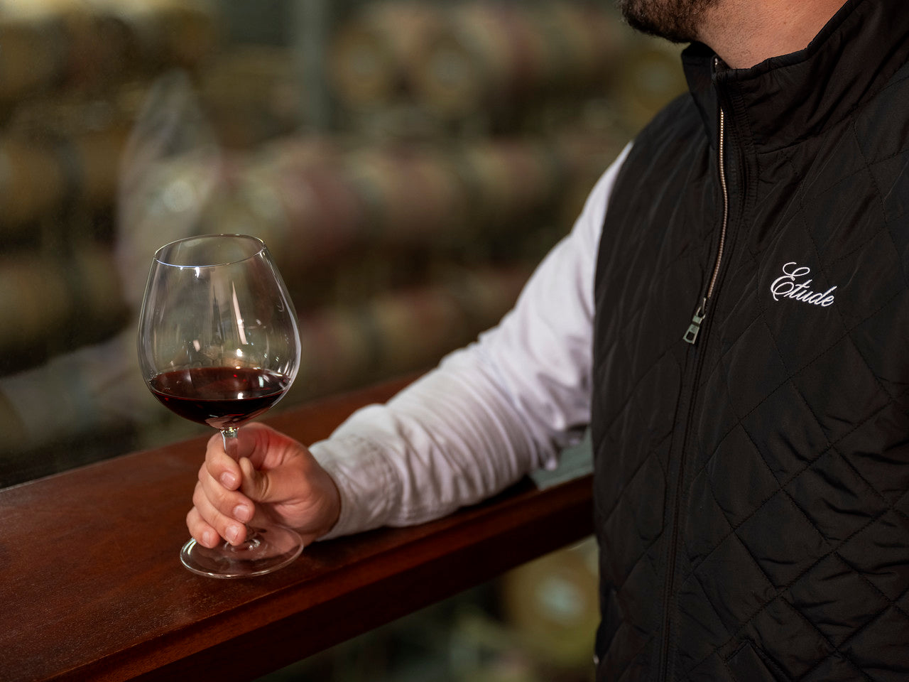 Man in black vest holding a glass of red wine