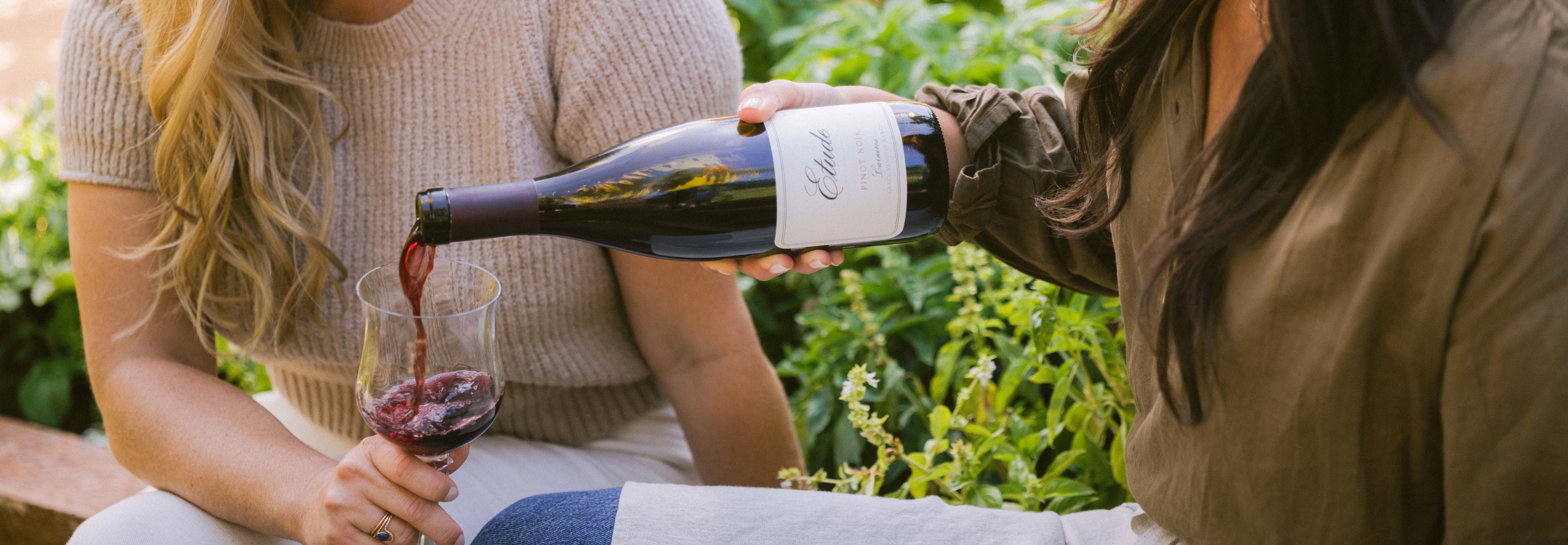 Woman pouring Etude Pinot Noir wine into a glass.