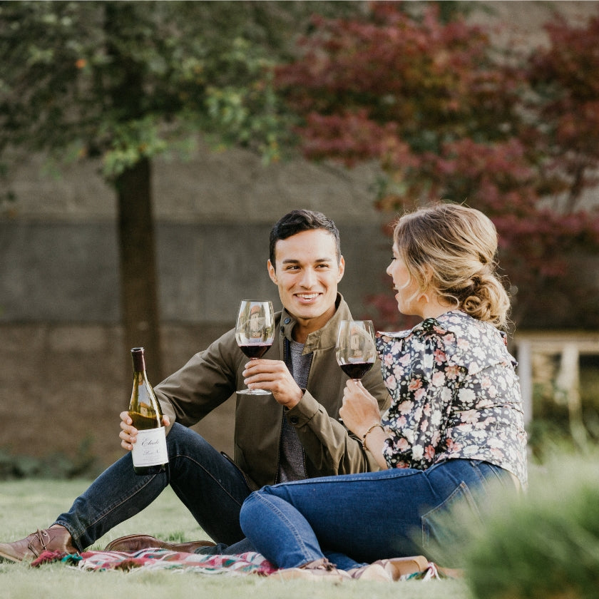 A couple enjoying Pinot Noir on a picnic blanket on the lawn at Etude