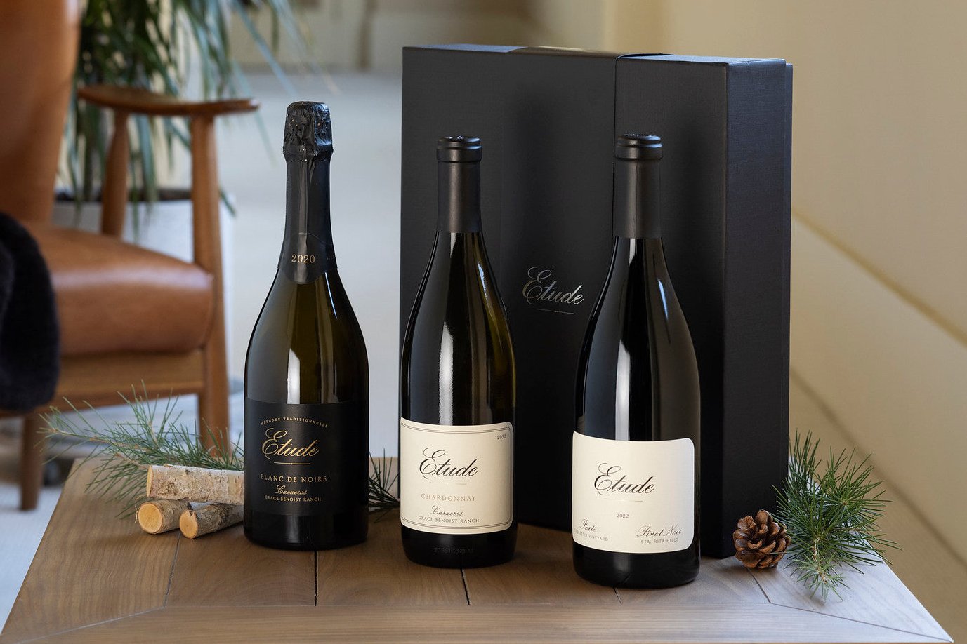Three Etude wines—Blanc de Noirs, Chardonnay, and Pinot Noir—in front of a black Etude gift box.